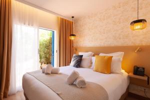 - une chambre avec un grand lit et des serviettes dans l'établissement Hôtel La Piscine, au Lavandou