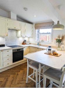 uma cozinha com armários brancos e uma mesa com cadeiras em Palm Cottage em Kent