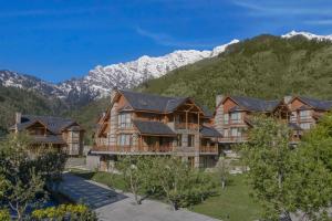 a large house with mountains in the background at Welcomhotel By ITC Hotels, Hamsa Manali in Manāli