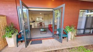 an open glass door with two chairs and a kitchen at Rise n' Shine - min stay 4 nights in Port Pirie