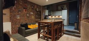 a kitchen and living room with a brick wall at Aux frais de la princesse - Gîte citadin 3 épis in Chimay