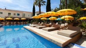 a pool with yellow umbrellas and lounge chairs and a swimming pool at Hôtel La Piscine in Le Lavandou