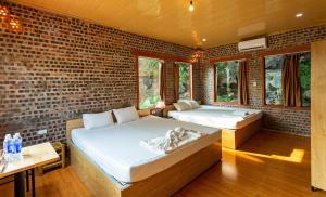 two beds in a room with a brick wall at Ham Rong Bungalow in Xuân Sơn