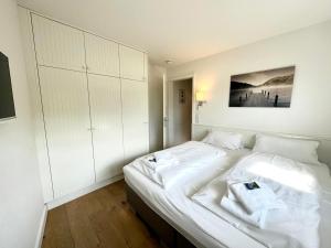 een witte slaapkamer met een groot bed met witte lakens bij Rothtraut Remise Whg5 in Wyk auf Föhr