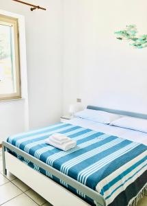 um quarto branco com uma cama com lençóis azuis e brancos em Appartamenti vicini al mare a Giglio campese em Campese