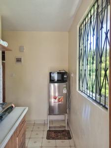 - une cuisine avec un réfrigérateur en acier inoxydable à côté d'une fenêtre dans l'établissement YellowMellow, à Kilifi