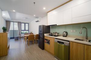 a kitchen with green and wooden cabinets and a table at HSuites Riverside Hotel and Apartment in Danang