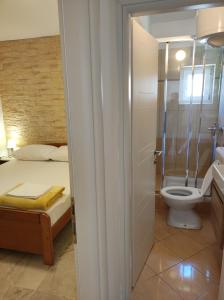 a bathroom with a toilet and a bed and a shower at Apartments Katica in Metajna
