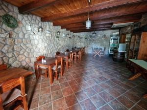 a restaurant with wooden tables and chairs in a stone wall at Guesthouse Barica in Crikvenica