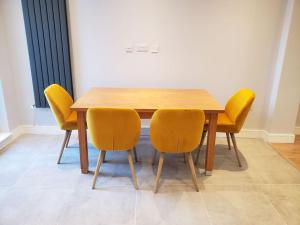 una mesa de madera con cuatro sillas amarillas alrededor en Huge 3 bedroom house in London E17 en Londres