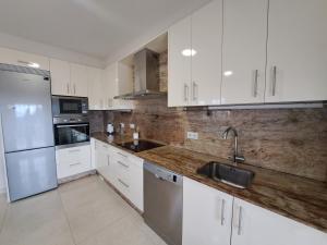 una cocina con armarios blancos y electrodomésticos de acero inoxidable en Samil, Vigo, chalet con finca, en Vigo