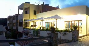 a white building with umbrellas in front of it at Miraluna Aparthotel in Lefkos Karpathou