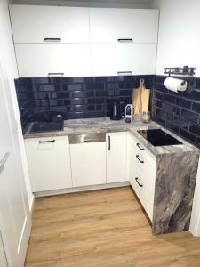 a kitchen with white cabinets and a black tile wall at Bei den Reymann´s in Nollingen