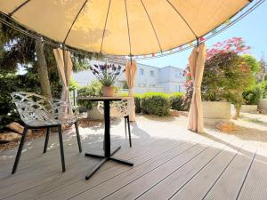einen Tisch und einen Stuhl unter einem Schirm auf einem Deck in der Unterkunft Korbstadt-Villa Rattan-Design mit Balkon, Garten, Arbeitsplatz, Küche in Lichtenfels
