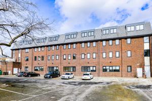a large brick building with cars parked in a parking lot at Hybrid Resi - London, Sutton, FREE on-site Car or Van parking in Cheam