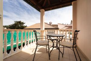 patio z krzesłami i stołem na balkonie w obiekcie Villa Cassia w miejscowości Mali Lošinj
