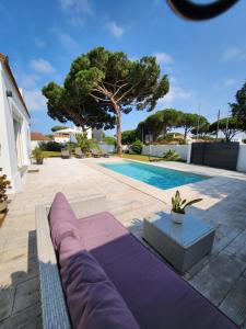 a swimming pool with a purple couch in front of a house at Villa yoli 26 chalet con piscina cerca de la playa in Chiclana de la Frontera