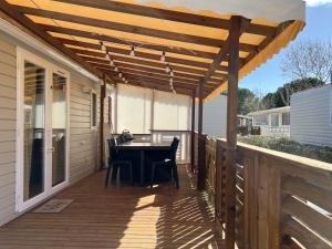 a patio with a table and chairs under a wooden pergola at Mobilhome La Carabasse Vias Plage in Vias