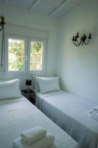 Duas camas num quarto branco com duas janelas em Sani Pine em Sani Beach