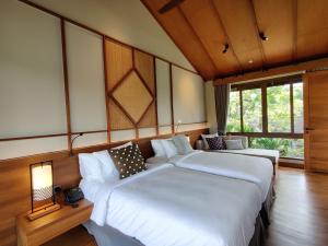 two beds in a room with two windows at Rarin Villas in Chiang Mai