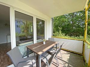 eine Veranda mit einem Holztisch und Stühlen auf dem Balkon in der Unterkunft Villa Störtebeker - FeWo 14 in Baabe
