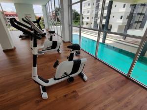 un gimnasio con 3 bicicletas estáticas y una piscina en Hygge Living Kampar (Near UTAR), en Kampar