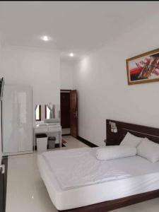 a white bedroom with a large bed and a desk at Cahaya Green Bali in Pesanggaran