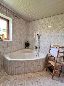 y baño con bañera y silla de madera. en Ferienhaus Praschberg en Niederndorferberg