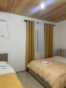 sypialnia z 2 łóżkami i oknem z zasłonami w obiekcie Lugina e Komanit w mieście Koman