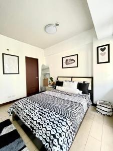 a bedroom with a large bed with a black and white blanket at Two Palm Tree Villas in Manila