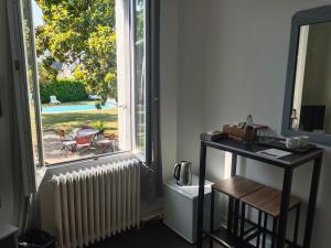 a room with a desk and a window with a table at Le Magnolia, chambre d'hôte au calme in Saumur