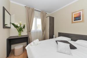 a bedroom with a white bed and a vase of flowers at Apartmani Perić 1 Meka Draga in Obrovac