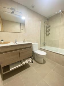 y baño con aseo, lavabo y bañera. en PreaMar apartamento acogedor con terraza, en Laxe