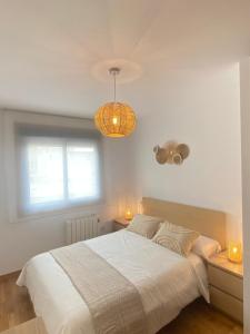 a bedroom with a bed and a window and a chandelier at PreaMar apartamento acogedor con terraza in Laxe