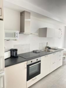 a kitchen with white cabinets and a black counter top at PreaMar Gran apartamento con terraza in Laxe +5 photos