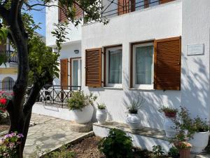 una casa bianca con finestre in legno e piante in vaso di Karagiozos Studios & Apartments a Skopelos Town