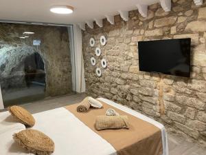 1 dormitorio con pared de piedra y TV de pantalla plana en Ereta Rooms Habitaciones baño privado, en Alicante