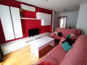 ein Wohnzimmer mit roten Wänden und 2 Sofas in der Unterkunft Apartamento El Alfar in Talavera de la Reina