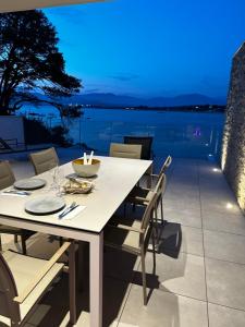 una mesa blanca y sillas en un patio con vistas al agua en RESIDENCE Neuve LE GALATEE PIED DANS L'EAU en Porticcio