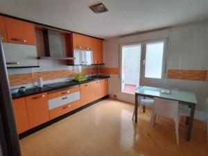 eine Küche mit orangefarbenen Schränken und einem Tisch darin in der Unterkunft Apartamento El Alfar in Talavera de la Reina