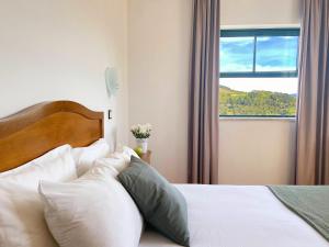 Un dormitorio con una cama con almohadas blancas y una ventana en Vinhais Hotel, en Vinhais