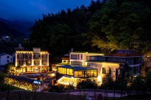 una casa grande con luces en el patio por la noche en Zhangjiajie Speak to Stone Art Holiday Hotel, en Zhangjiajie