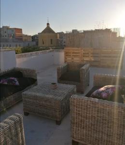 a patio with wicker chairs and tables on a roof at Dimora di Paola in Martina Franca