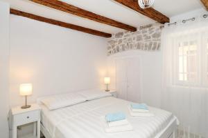 ムルテルにあるStone House apartments in the center of Murter townの白いベッドルーム(白いベッド1台、ランプ2つ付)