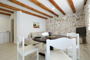 ムルテルにあるStone House apartments in the center of Murter townの白い椅子とテーブル、石の壁のあるダイニングルーム