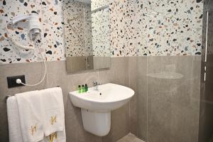 uma casa de banho com um lavatório branco e um chuveiro em Hotel Vino em Durrës