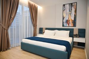 a bedroom with a blue and white bed and a window at Hotel Vino in Durrës
