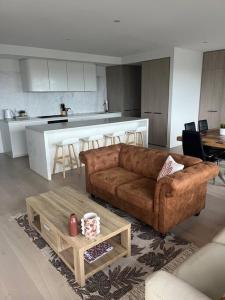 a living room with a brown couch and a kitchen at Welcome to Skyview - top level in Glen Waverley