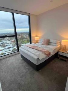 a bedroom with a bed with a large window at Welcome to Skyview - top level in Glen Waverley
