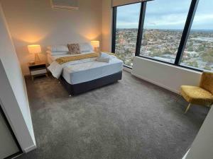 a bedroom with a bed and large windows at Welcome to Skyview - top level in Glen Waverley